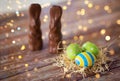 Easter eggs in straw nest and chocolate bunnies Royalty Free Stock Photo