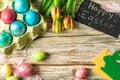 Easter, Easter eggs in a tray, on a wooden board, with tulips top view, inscription Happy Easter
