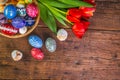 Easter eggs with tulips on weathered wooden background