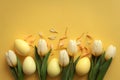 Easter eggs and tulips on a yellow background Royalty Free Stock Photo