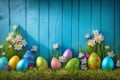 Easter eggs on turf grass and blue wooden wall with spring vivid flowers