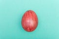 Easter Eggs on turquoise background. Red egg handmade new style of colouring form flower on a colored cardboard. Pattern, easter c