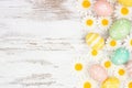 Easter eggs and white daisy flowers side border against a rustic white wood background Royalty Free Stock Photo