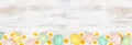 Easter eggs and white daisy flowers bottom border against a rustic white wood banner background Royalty Free Stock Photo