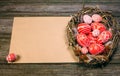 Easter eggs with white pattern inside bird nest on right side of old sheet of paper on wood board. Top view horizontal background Royalty Free Stock Photo