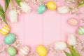 Easter eggs and white spring tulip flower frame against a pink wood background Royalty Free Stock Photo