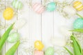 Easter eggs and white spring tulip flower frame against a white wood background Royalty Free Stock Photo