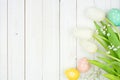 Easter eggs and white spring tulip flower side border against a white wood background Royalty Free Stock Photo