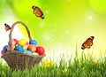 Easter eggs in wicker basket on green grass and butterflies against background Royalty Free Stock Photo
