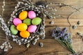 Easter eggs in willow nest, flowers over wooden rustic background Royalty Free Stock Photo