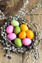 Easter eggs in willow nest, flowers over wooden rustic background Royalty Free Stock Photo