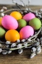 Easter eggs in willow nest, flowers over wooden rustic background Royalty Free Stock Photo