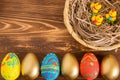 Easter eggs on wooden background next to basket with baby chicken Royalty Free Stock Photo