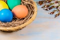 Easter eggs in a wooden basket next to green spring twigs Royalty Free Stock Photo