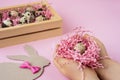 Easter eggs in a wooden box. Hands holding a nest with an egg on a pink background. Royalty Free Stock Photo