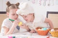 Easter festival: children paint easter eggs at the table. A boy in a rabbit costume looks cunningly at the work of the older siste