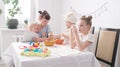 Easter Festival: The family at the table prepare for the holiday. Daughter put a pattern on the egg. Royalty Free Stock Photo