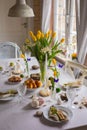 Easter festive spring table setting decoration, eggs in nest, fresh yellow tulips, marshmallows, selective focus Royalty Free Stock Photo