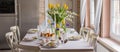 Easter festive spring table setting decoration, eggs in nest, fresh yellow tulips, marshmallows, selective focus banner Royalty Free Stock Photo