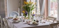 Easter festive spring table setting decoration, eggs in nest, fresh yellow tulips, marshmallows, selective focus banner Royalty Free Stock Photo