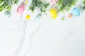 Easter composition with colored eggs and green plants on white background. Royalty Free Stock Photo