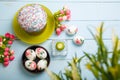 Easter flatlay composition with decorated eggs, unfocused flowers, burning candle, Easter bread or cake with glaze