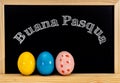 Easter frame with painted eggs and chalkboard. Happy Easter in white chalk. Happy Easter in italian : buana pasqua