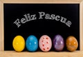 Easter frame with painted eggs and chalkboard. Happy Easter in white chalk. Happy Easter in spanish : feliz Pascua