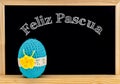 Easter frame with painted eggs and chalkboard. Happy Easter in white chalk. Happy Easter in spanish : feliz Pascua