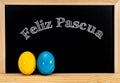 Easter frame with painted eggs and chalkboard. Happy Easter in white chalk. Happy Easter in spanish : feliz Pascua