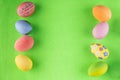 Easter frame. Variety of yellow, pink, green, blue, orange painted Easter eggs lay on green background. Top view, flatly