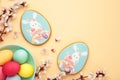 Easter gingerbread and eggs with seasonal flowers on beige background. Sweet Easter concept, greeting card