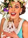 Easter girl holding bunny. Woman with holiday spring flowers hairstyle.