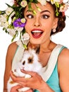 Easter girl holding bunny. Woman with holiday spring flowers hairstyle.