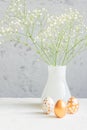 Easter golden eggs and bouquet of gypsophila flowers on the gray wall background. Festive cozy still life for holiday. Interior Royalty Free Stock Photo