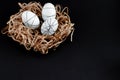 Easter goldenand white decorated eggs in nest on black background . Minimal easter concept copy space for text. Top