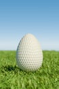 Easter golf ball shaped like an egg on grass under a clear blue sky. Royalty Free Stock Photo