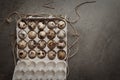 Easter gray background with a in cardboard packaging of quail eggs. Top view. Copy space.