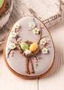 Easter gray cookie with decorative easter eggs and flowers near white cutting boards