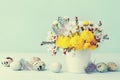 Easter greeting card with colorful flowers, feather and quail eggs on vintage blue background. Beautiful spring composition.