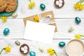 Easter greeting card in frame made of quail eggs, cup of cappuccino, spring flowers and biscuits