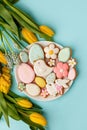 Easter greeting card with fresh tulip flowers, Gingerbread cookies - Easter eggs, bird, bunny and flowers on white plate, top view Royalty Free Stock Photo