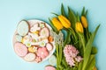 Easter greeting card with fresh tulip flowers, Gingerbread cookies - Easter eggs, bunny and flowers on white plate, top view with Royalty Free Stock Photo