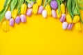 Easter greeting card. Multicolored easter eggs and tulips on yellow background. Easter concept