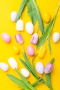 Easter greeting card. Multicolored easter eggs and tulips on yellow background. Easter concept