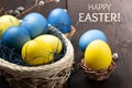 Easter greeting card - several colored eggs in a basket and on a dark wooden table with pussy-willow twigs and the Royalty Free Stock Photo