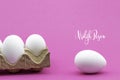 Vrolijk Pasen, Happy Easter white eggs in an egg carton on a pink background. Royalty Free Stock Photo