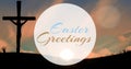 Easter greetings text on silhouette crucifix on land against sky at sunrise