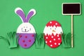 Easter hand made decorations: festive plastic foam bunny and egg with blackboard isolated on green background Royalty Free Stock Photo