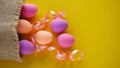 Easter with a hare glass figurine, colored chicken eggs and a pink ribbon on a yellow background